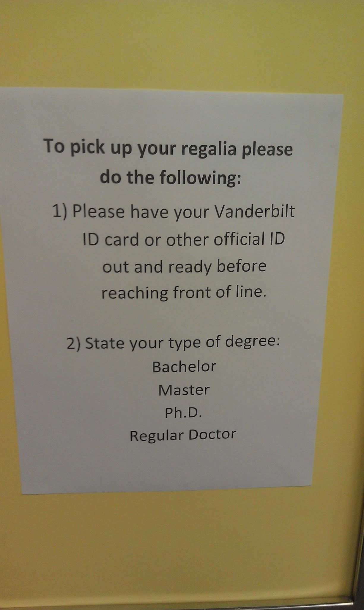 Sign stating: "To pick up your regalia please do the following: 1) Please have your Vanderbilt ID card or other official ID out and ready before reaching front of line. 2) State your type of degree: Bachelor Master Ph.D. Regular Doctor"