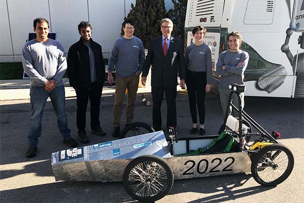 Secretary Perry and USU GEAR UP team pose in front of Green Power race car